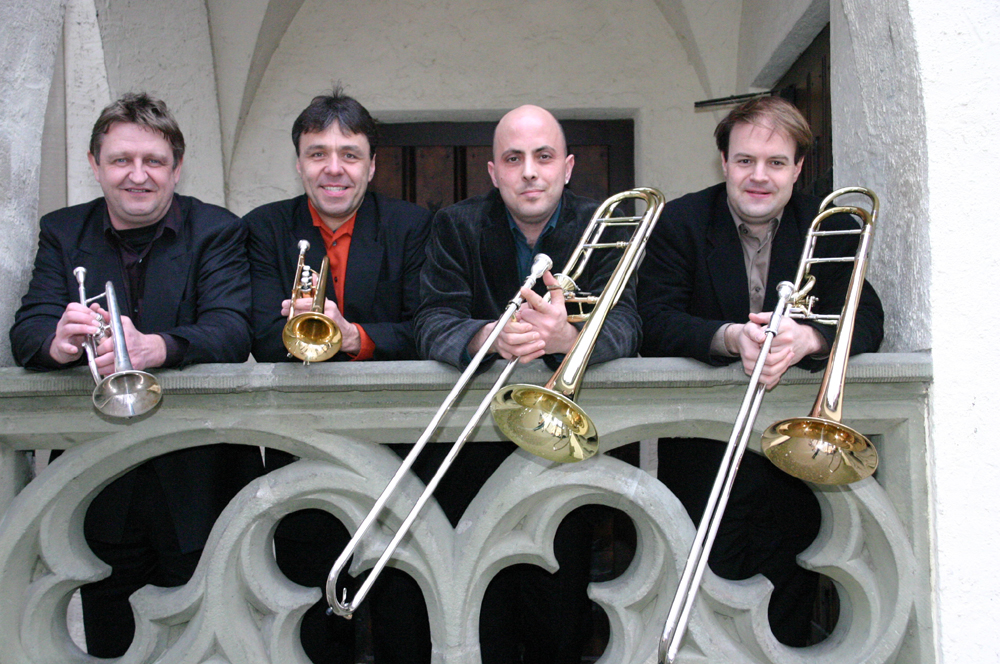 Vier Musiker mit Instrumenten am Geländer.