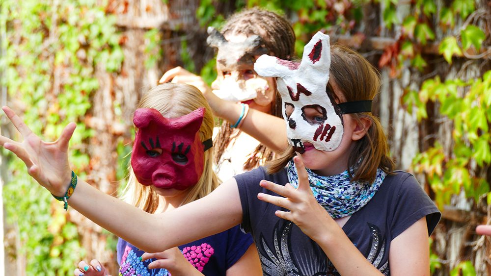 Drei Kinder mit Masken.