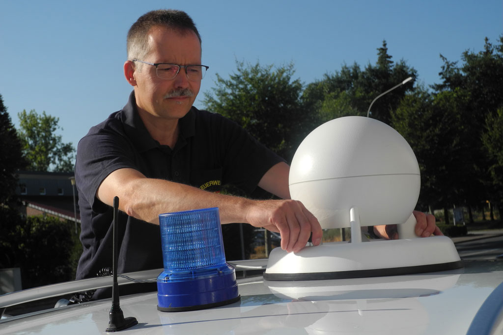 Leiter der Funkwerkstatt bei der Feuerwehr Paderborn montiert Sirene auf Fahrzeugdach.