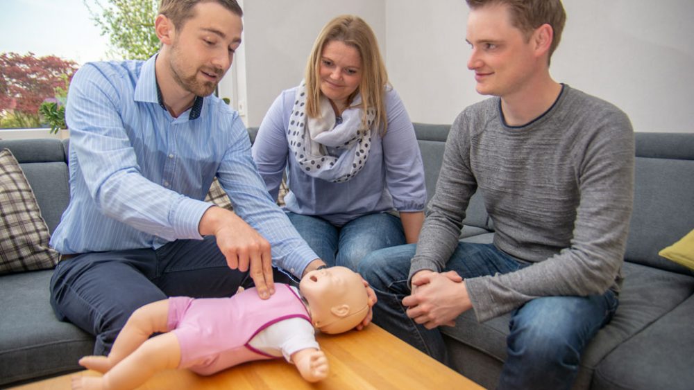 Jan-Niklas erläutert Julia und Daniel am Baby-Übungsmodell wichtige Handgriffe.