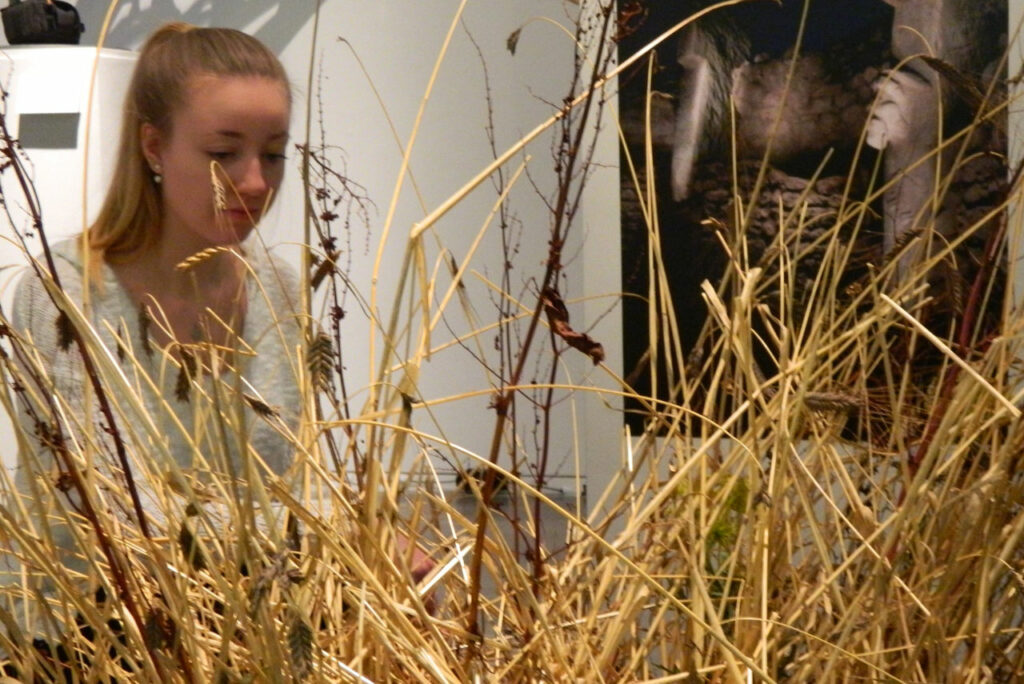 Mädchen kniet vor Weizenähren.