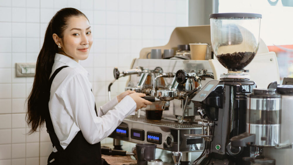 Mädchen als Barista an Espressomaschine